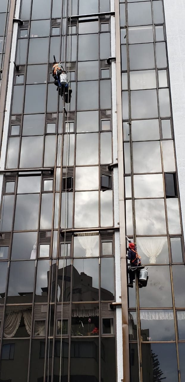 Técnico en descenso sobre fachada de torre de vidrio